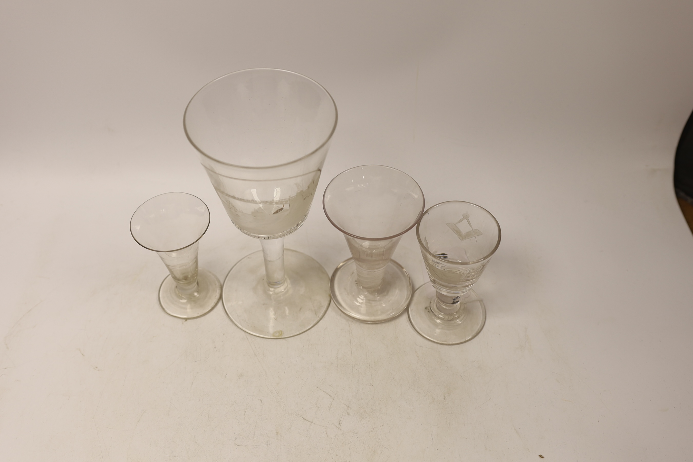 Four late 18th century drinking glasses; a DSOT stem toast masters glass, one with wheel engraved Masonic symbols, and a large wheel engraved goblet decorated with a view of Sunderland bridge, 20cm high